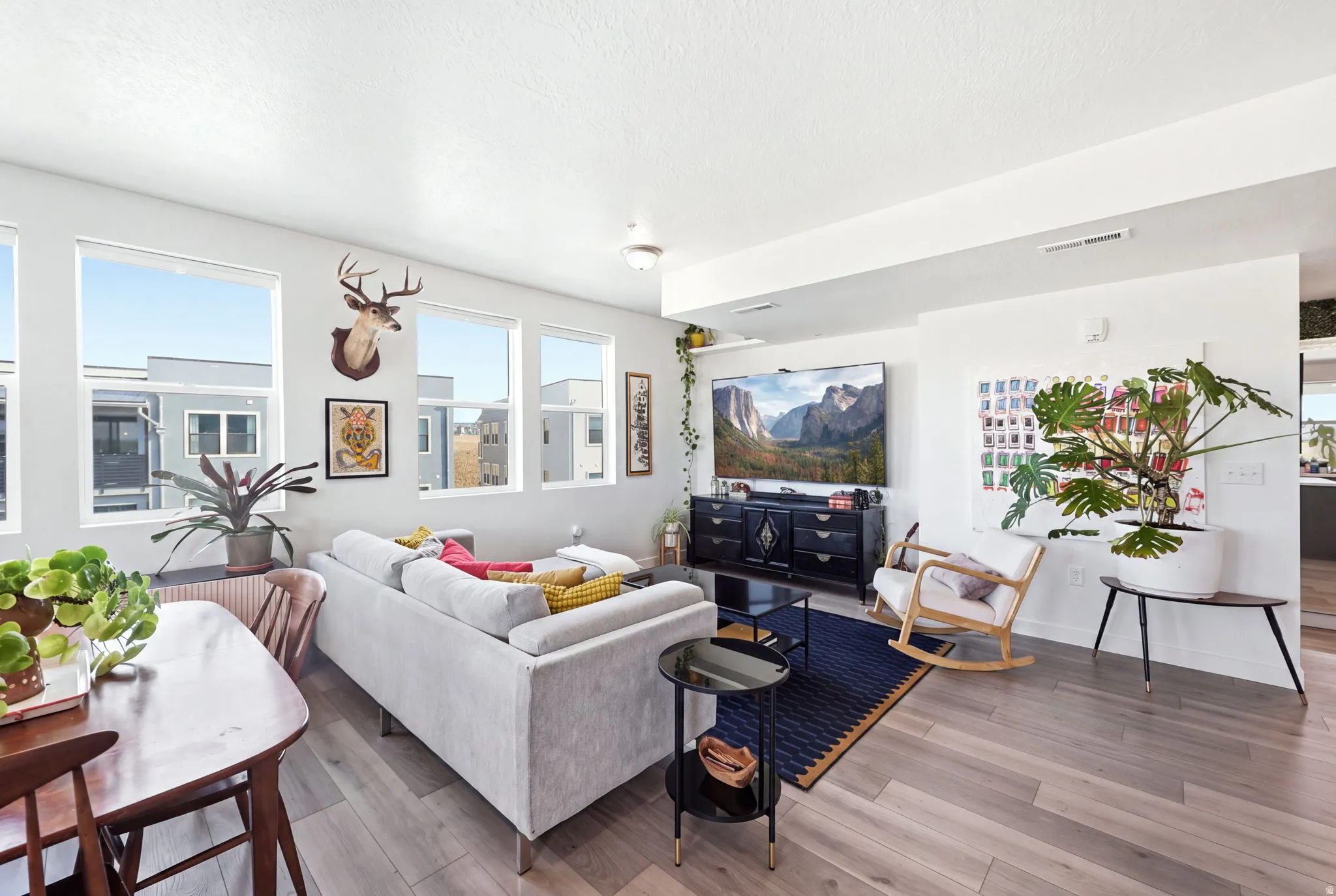 Recessed lighting, wood-finish flooring, multiple large windows, and a built-in media console