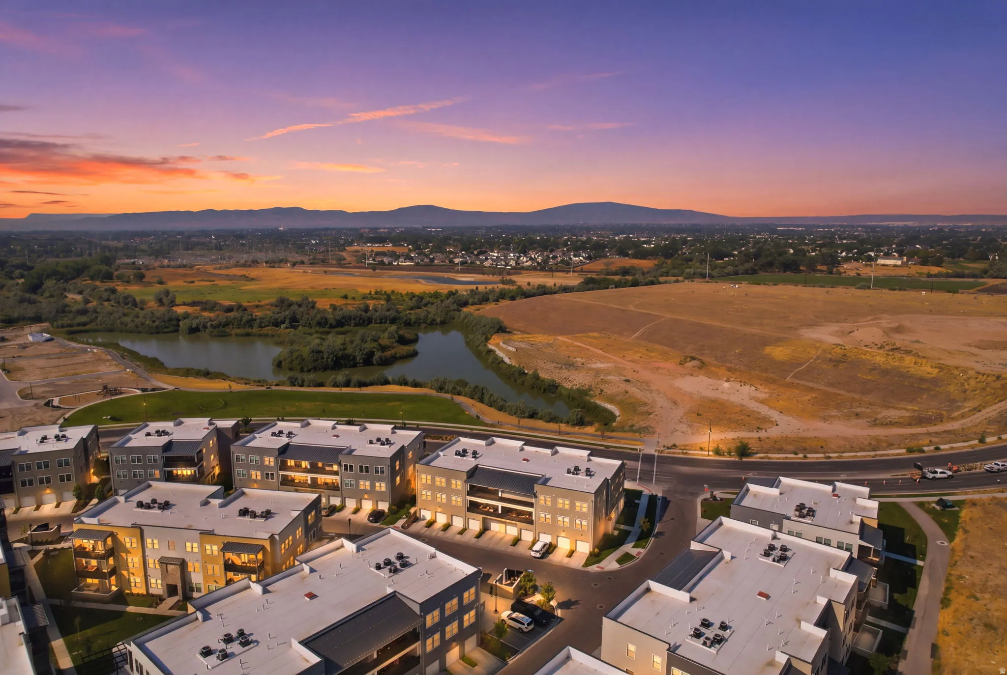 Modern multi-story buildings with balconies, a paved road, and distant mountainous terrain