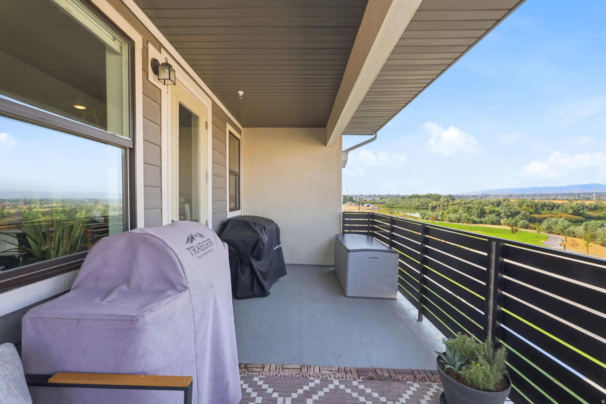 Spacious balcony featuring a durable concrete floor, horizontal slat railing, and exterior wall sconce