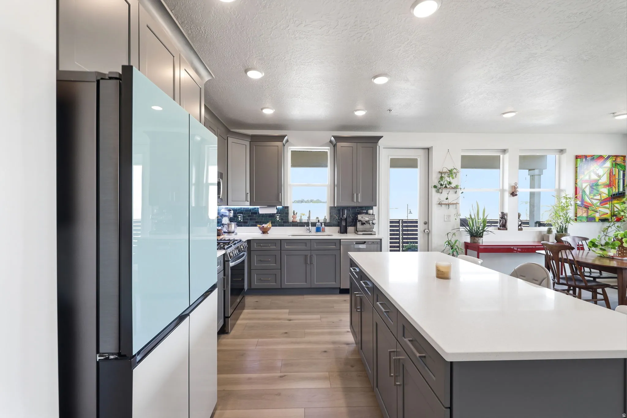 Modern kitchen featuring recessed lighting, a large center island with a light-colored countertop, gray cabinetry, and wood-finish flooring