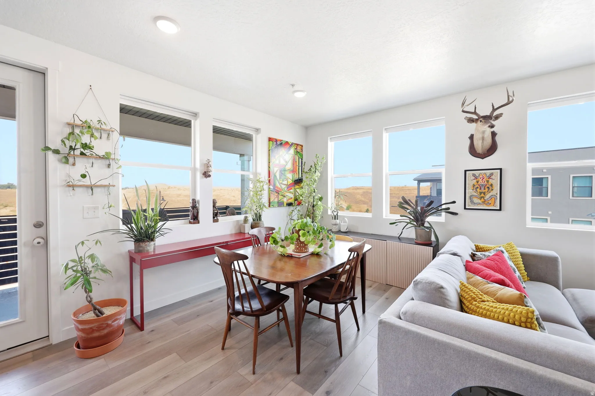 Recessed ceiling lighting, multiple large windows, wood-finish flooring, built-in lower cabinetry, and a private exterior door