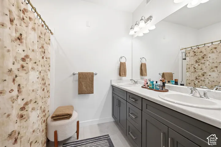 Dual vanity with undermount sinks, gray shaker-style cabinetry, and a full-width mirror