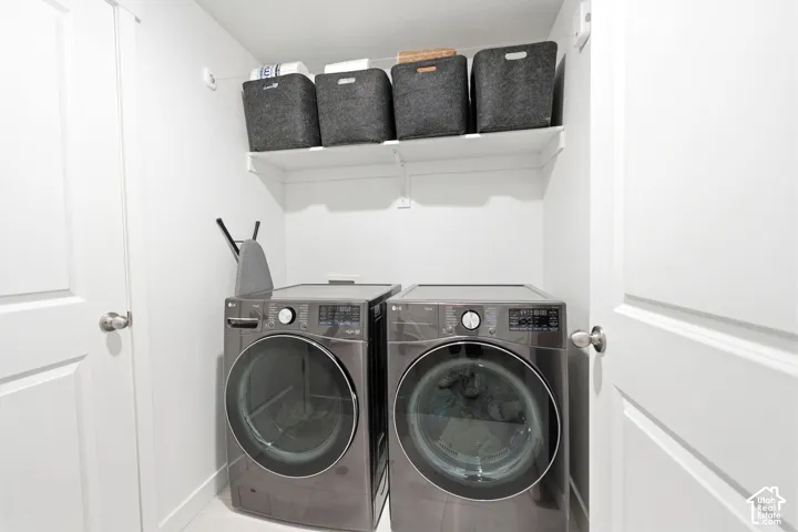 Integrated laundry closet with white shelving and a modern washer and dryer