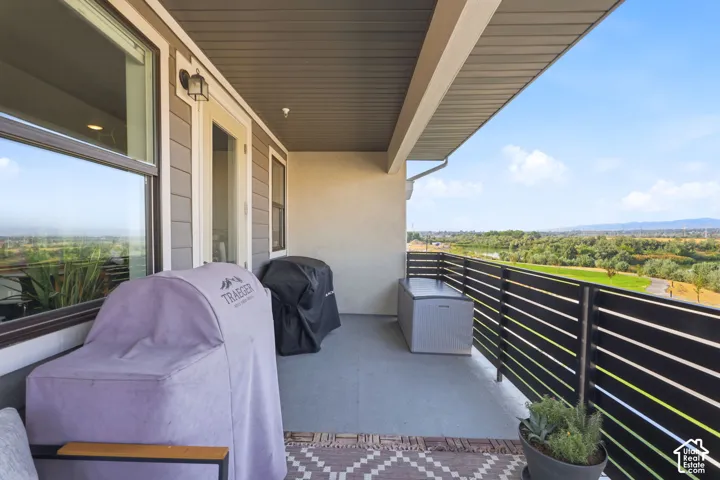 Spacious balcony featuring a durable concrete floor, horizontal slat railing, and exterior wall sconce