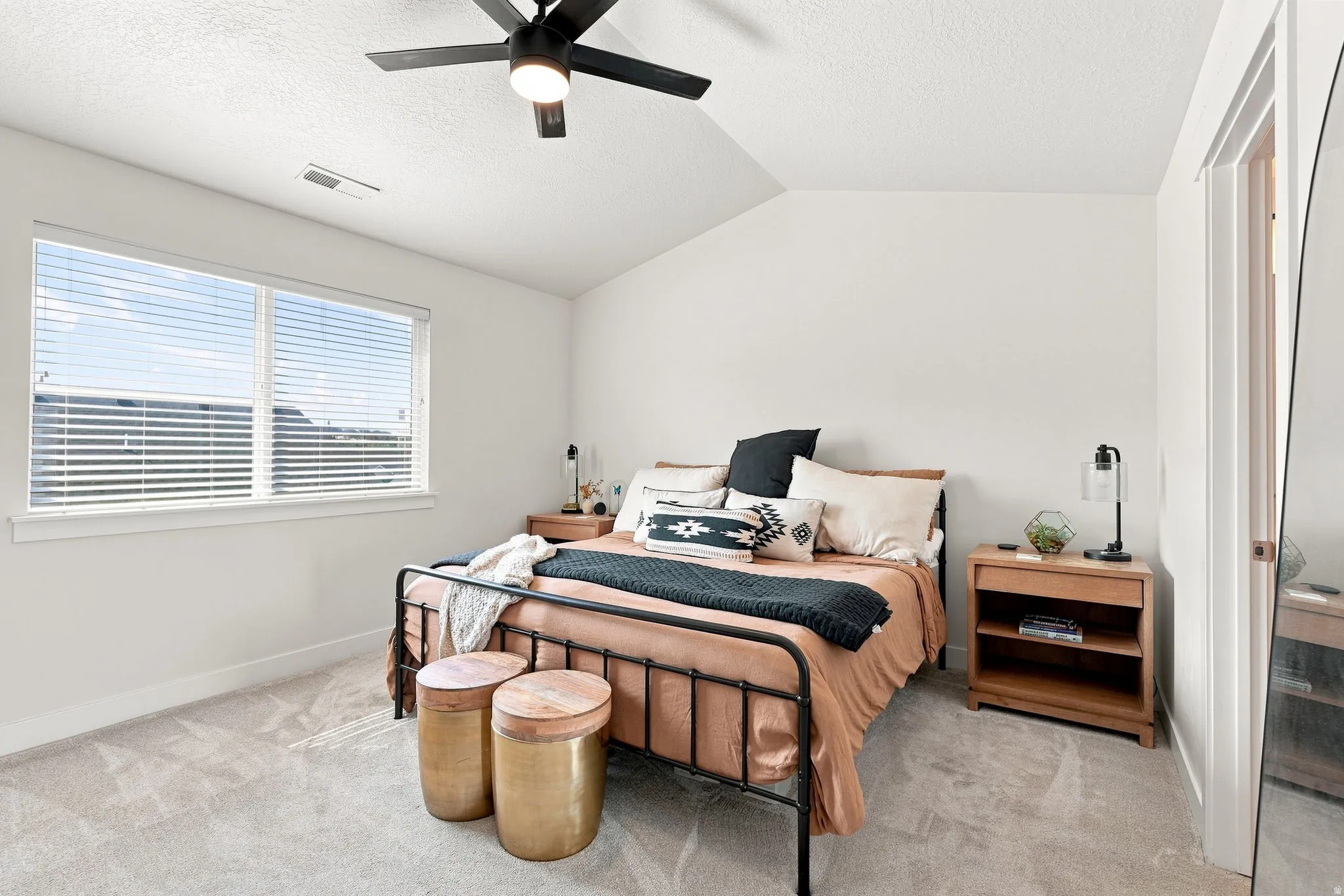 Primary Suite, vaulted ceiling with a flush-mount ceiling fan and integrated lighting, large window with horizontal blinds, light-toned carpeting, and white walls