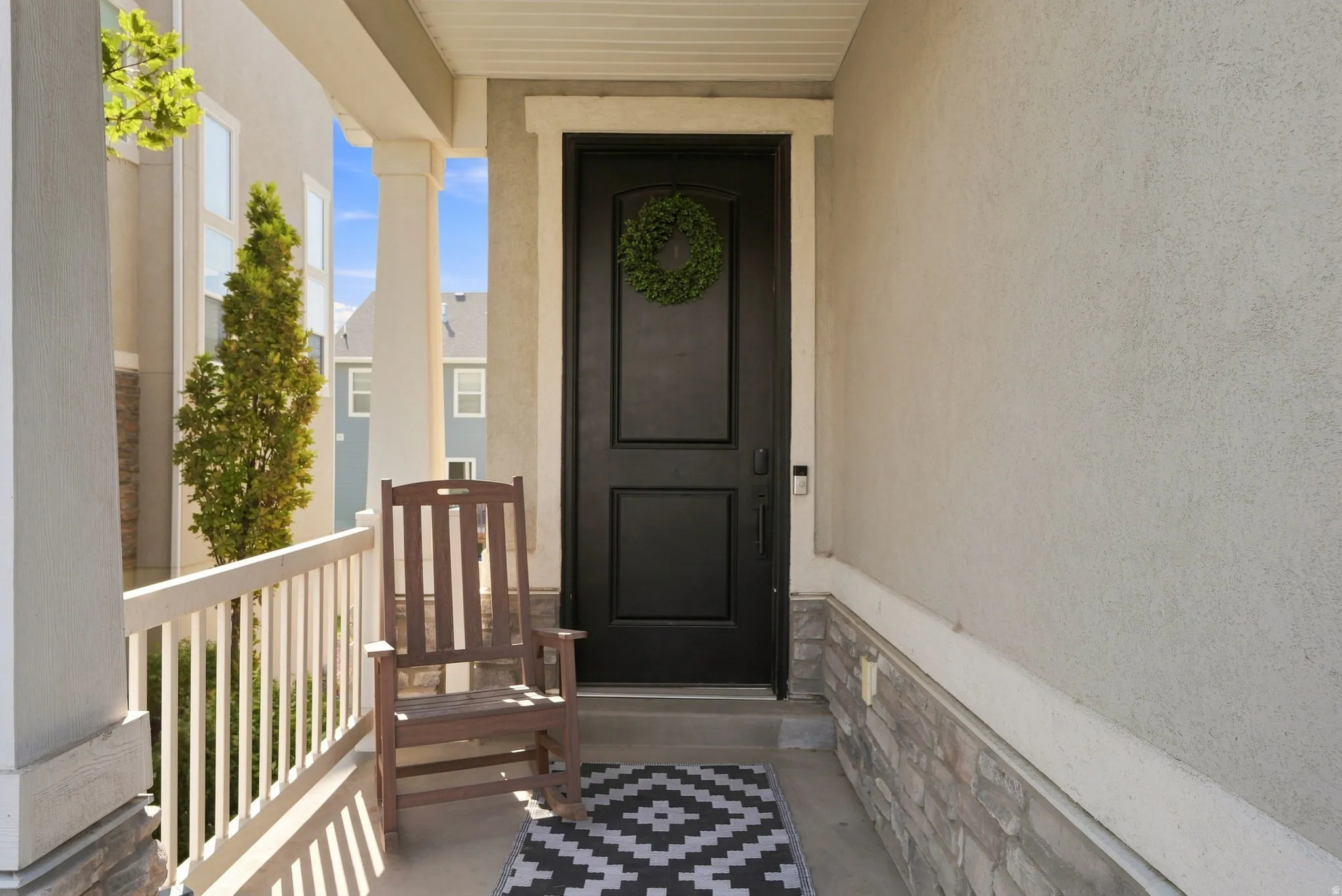 Covered porch with stone veneer base, white railing, and columns