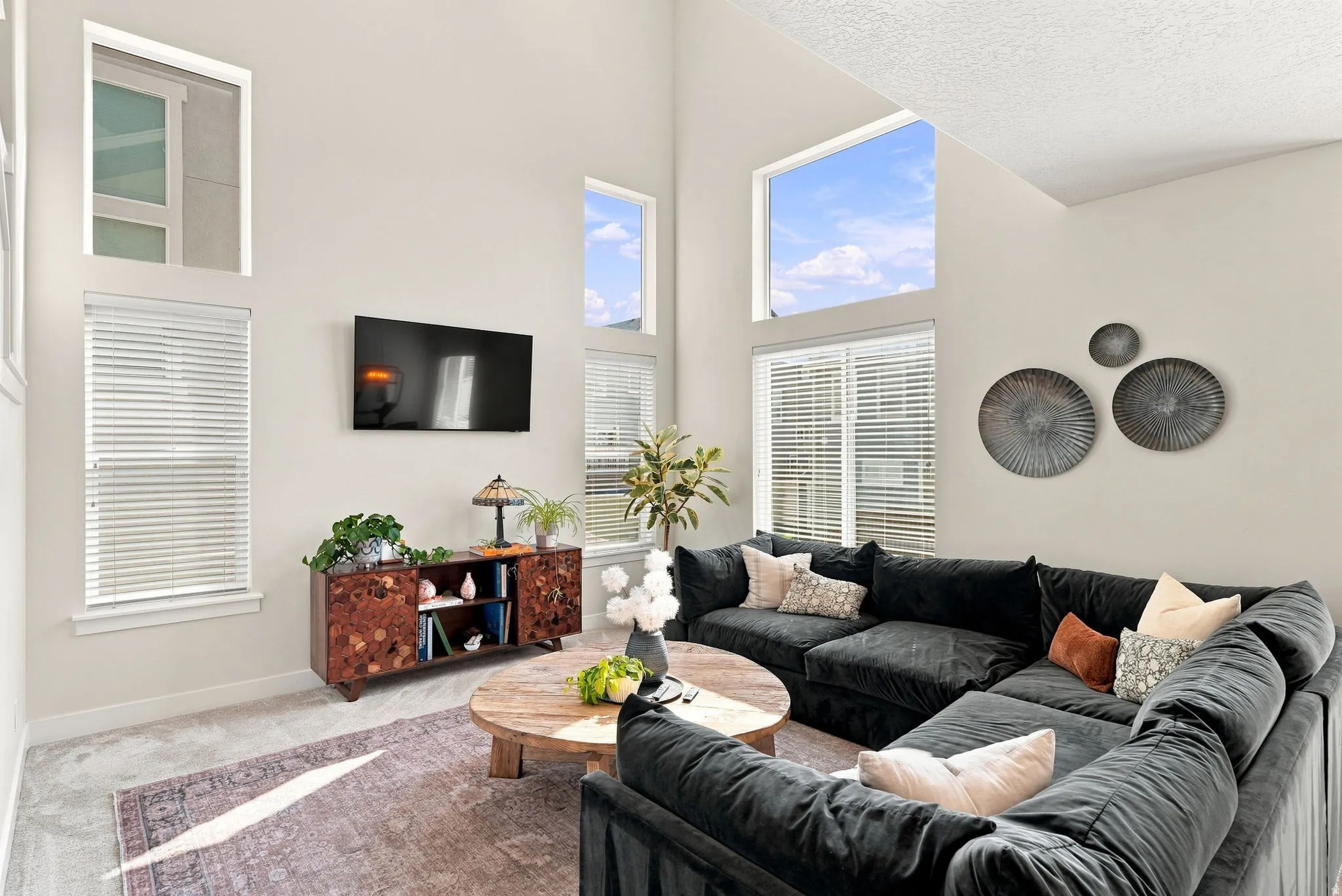 Vaulted ceiling with multiple upper windows, neutral wall tones, and recessed lighting