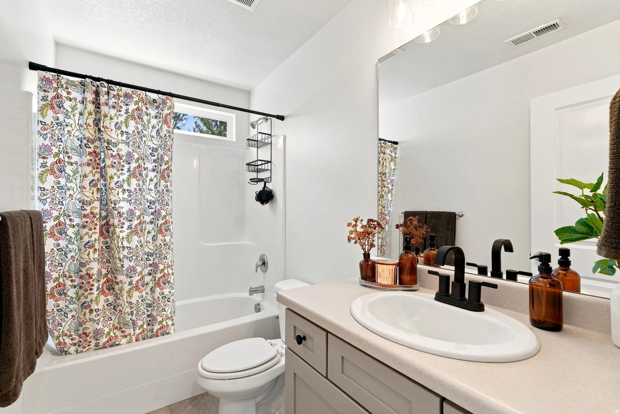 Bathroom featuring a single vanity with an integrated sink, matte black faucet, and a large wall-mounted mirror