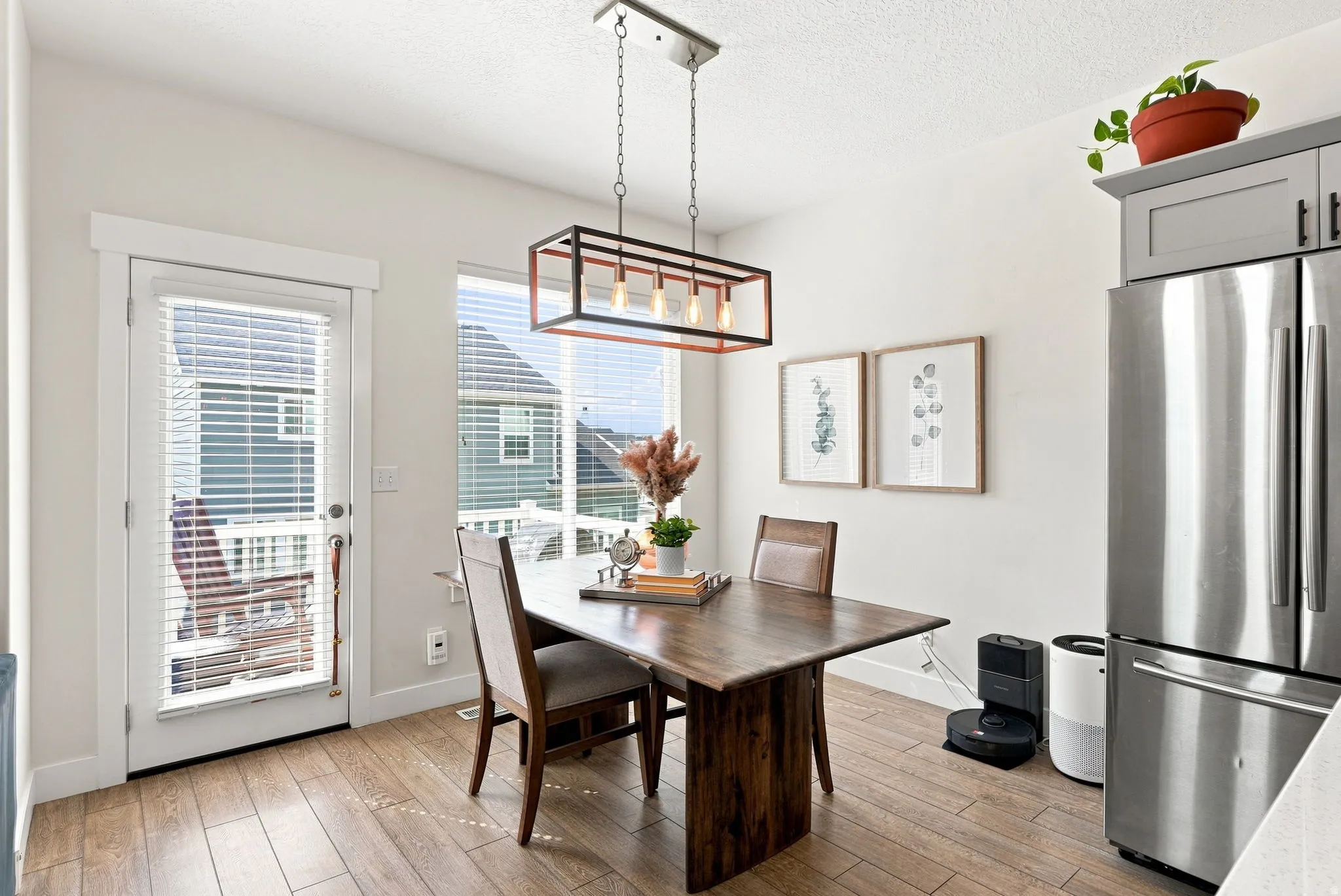 Wood-finish flooring, full-light exterior door, large window with blinds, stainless steel refrigerator, and recessed lighting