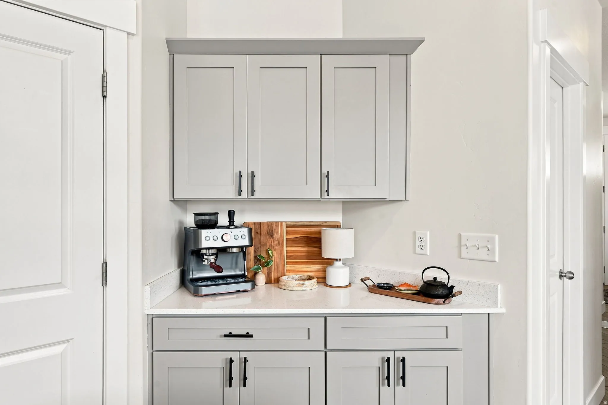 Built-in cabinetry with light gray shaker-style doors, black hardware, and white countertops