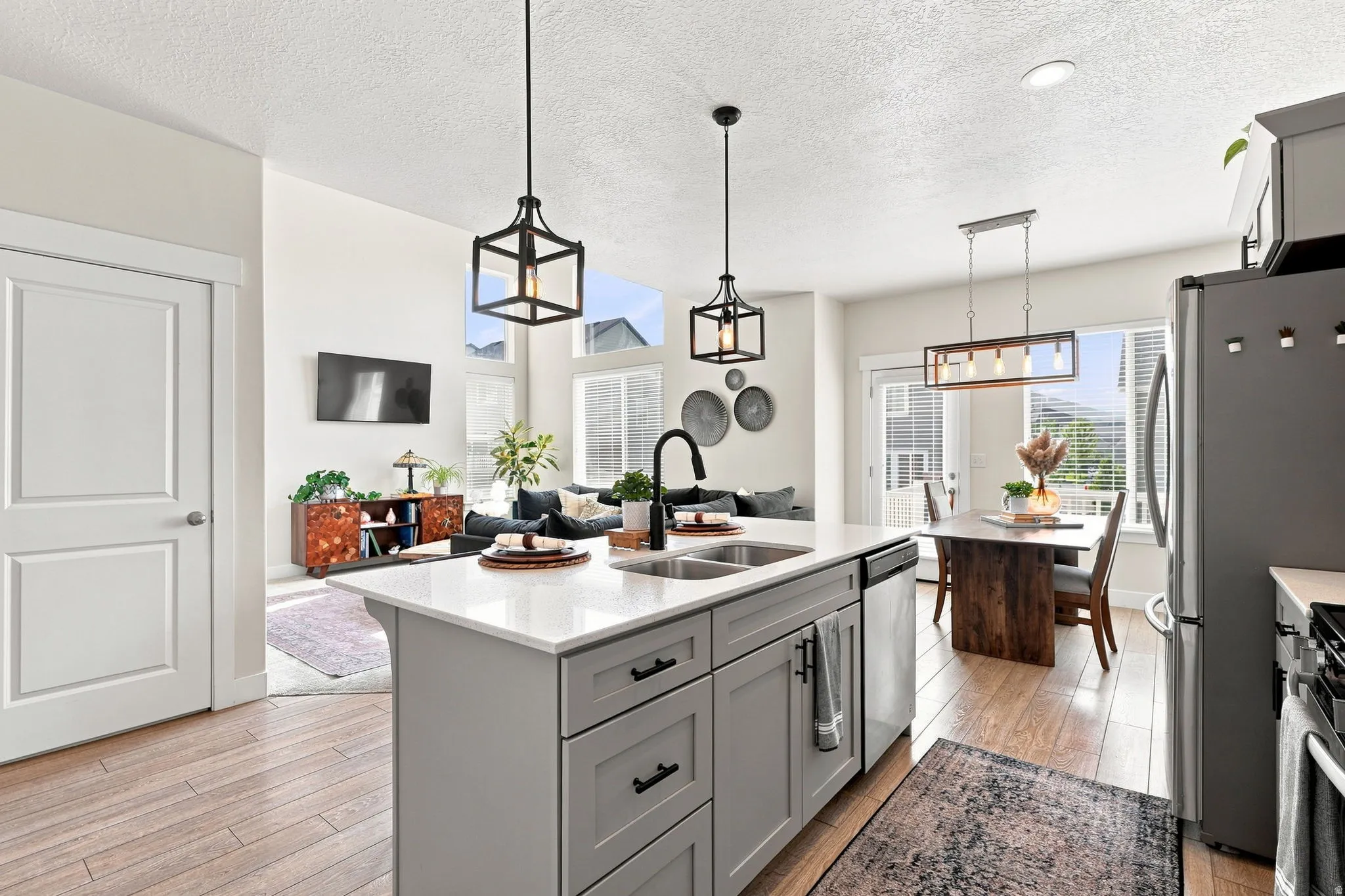 Central kitchen island with white countertop, dual basin sink, and pendant lighting