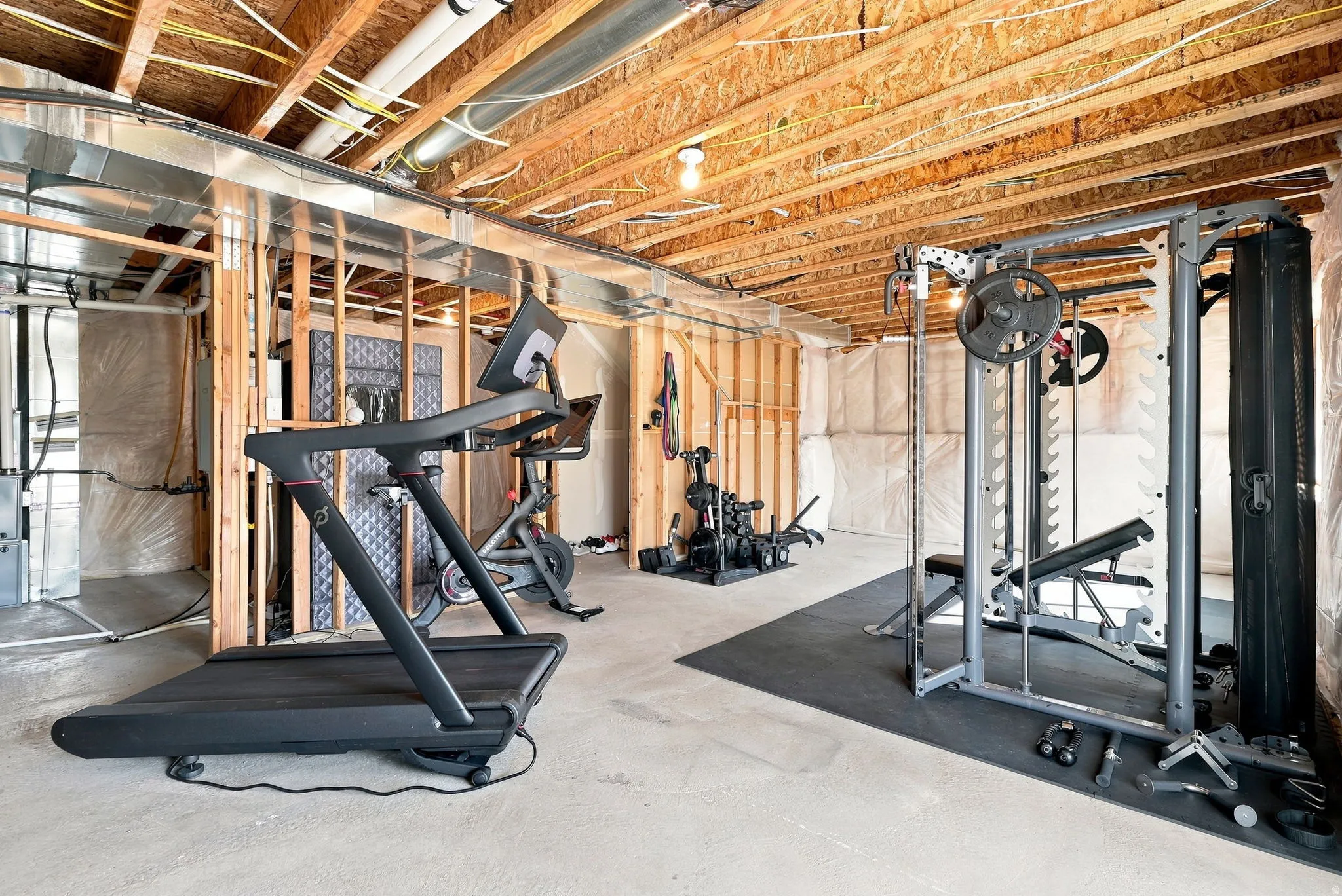 Unfinished basement featuring exposed wood joists, concrete flooring, and partial wall framing