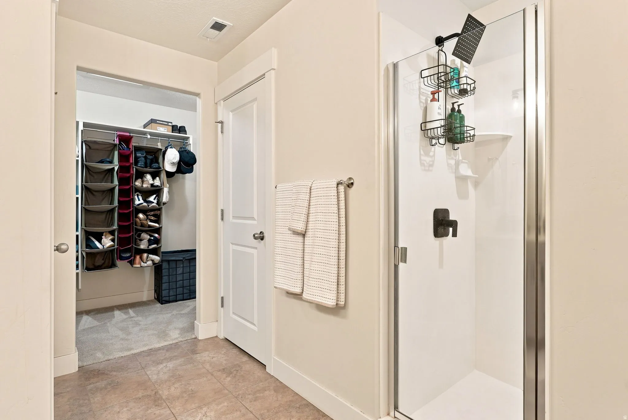 Primary Bath, enclosed shower with dark bronze fixtures, white paneling, and clear glass door