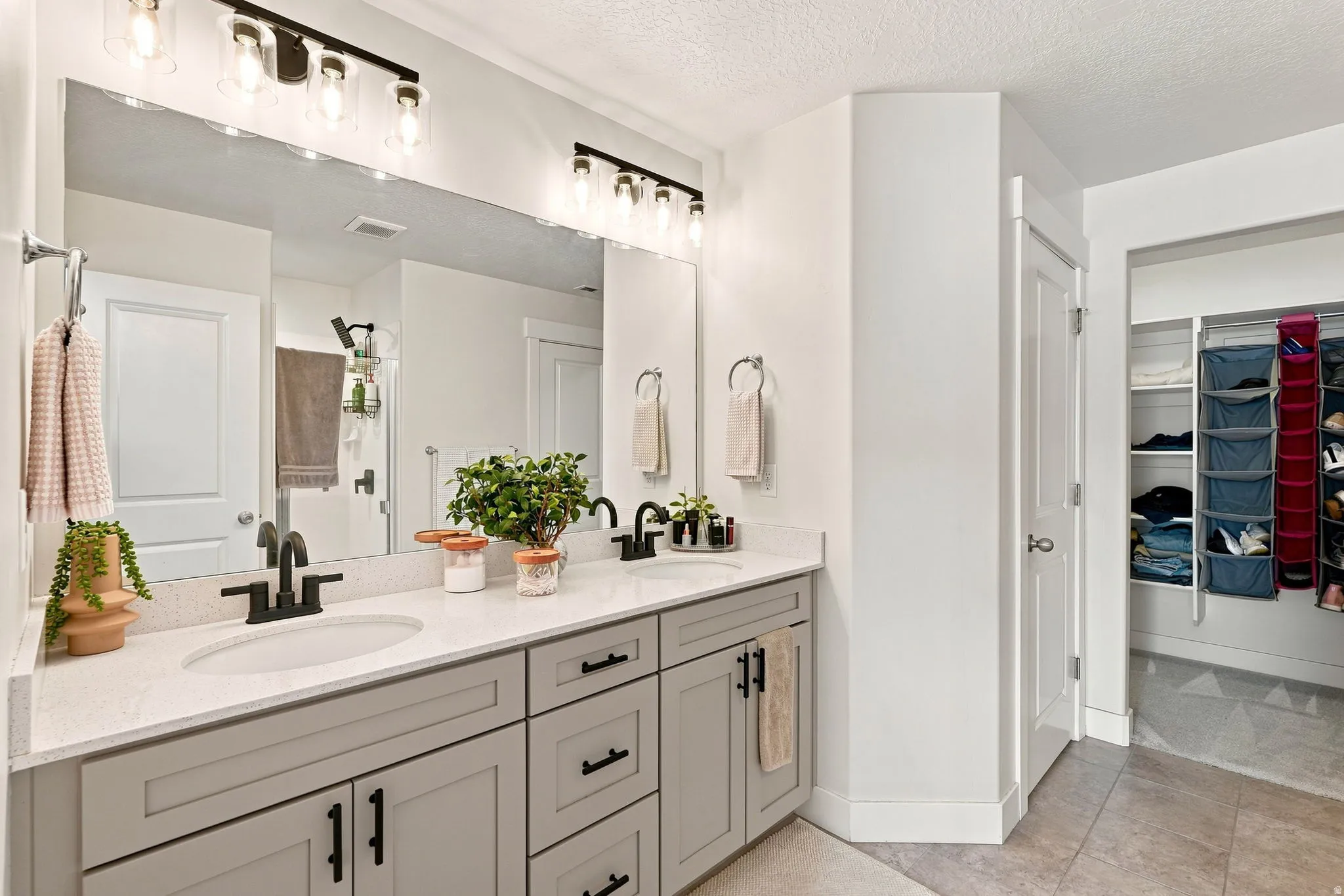 Primary Bath, dual vanity with light gray cabinetry, matte black hardware, and an expansive mirror