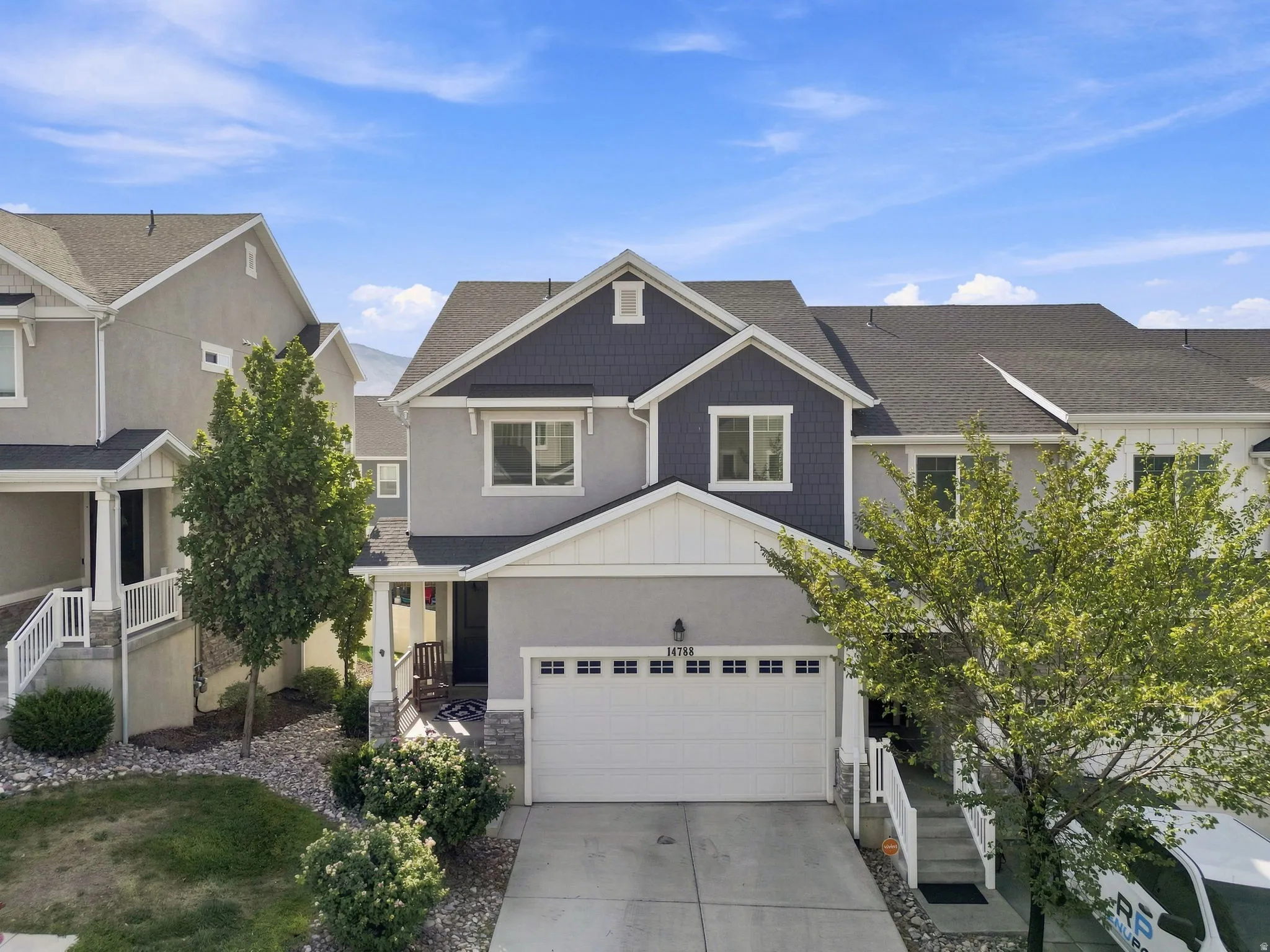 Two-story exterior featuring a stone accent foundation, attached two-car garage, and a covered entryway
