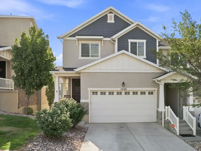 Two-story residence featuring a two-car garage, covered entry, and mixed material exterior with stone and siding accents