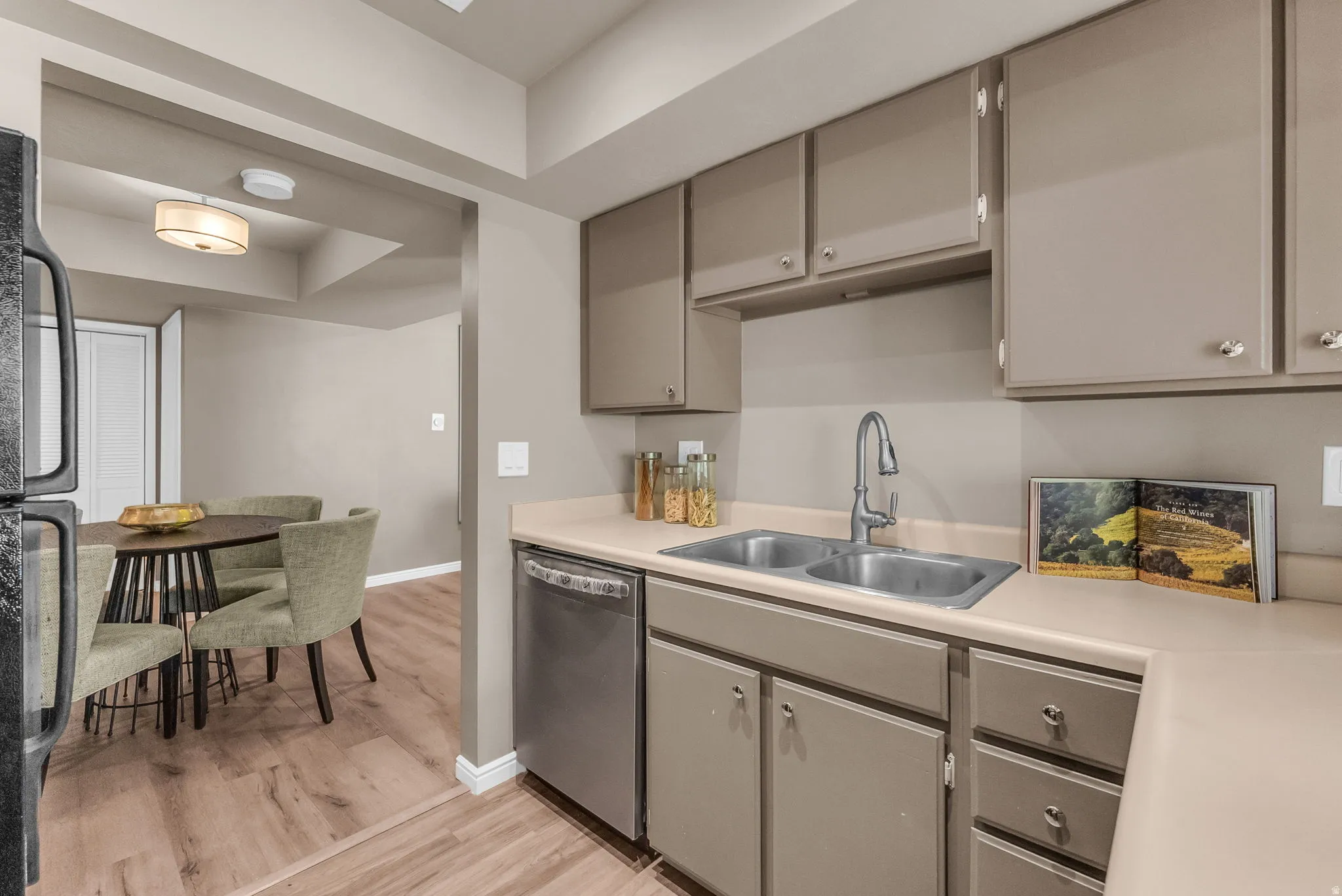 Modern kitchen featuring stainless steel appliances, including a dishwasher and under-counter refrigerator drawers, paired with soft-close cabinetry in a neutral finish