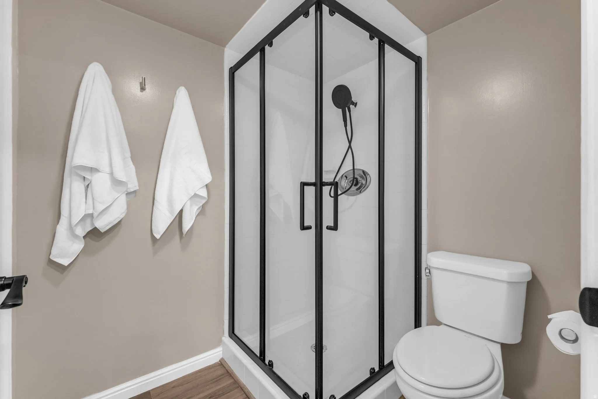 Corner shower with black framed enclosure and matte black fixtures