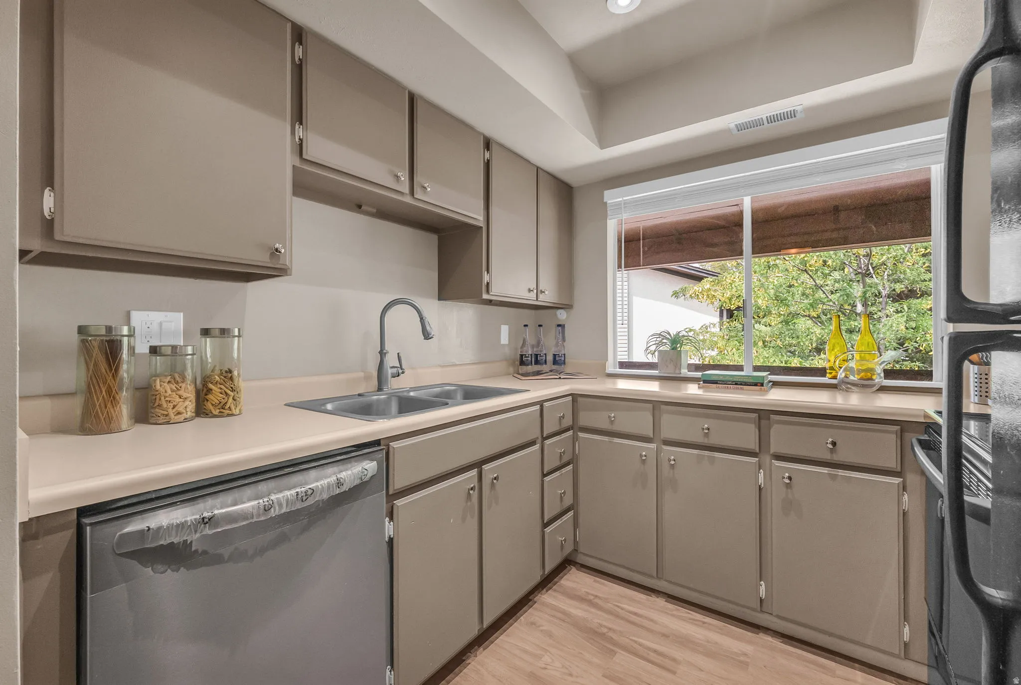 Kitchen featuring wood-finish flooring, a double basin sink, and a dishwasher