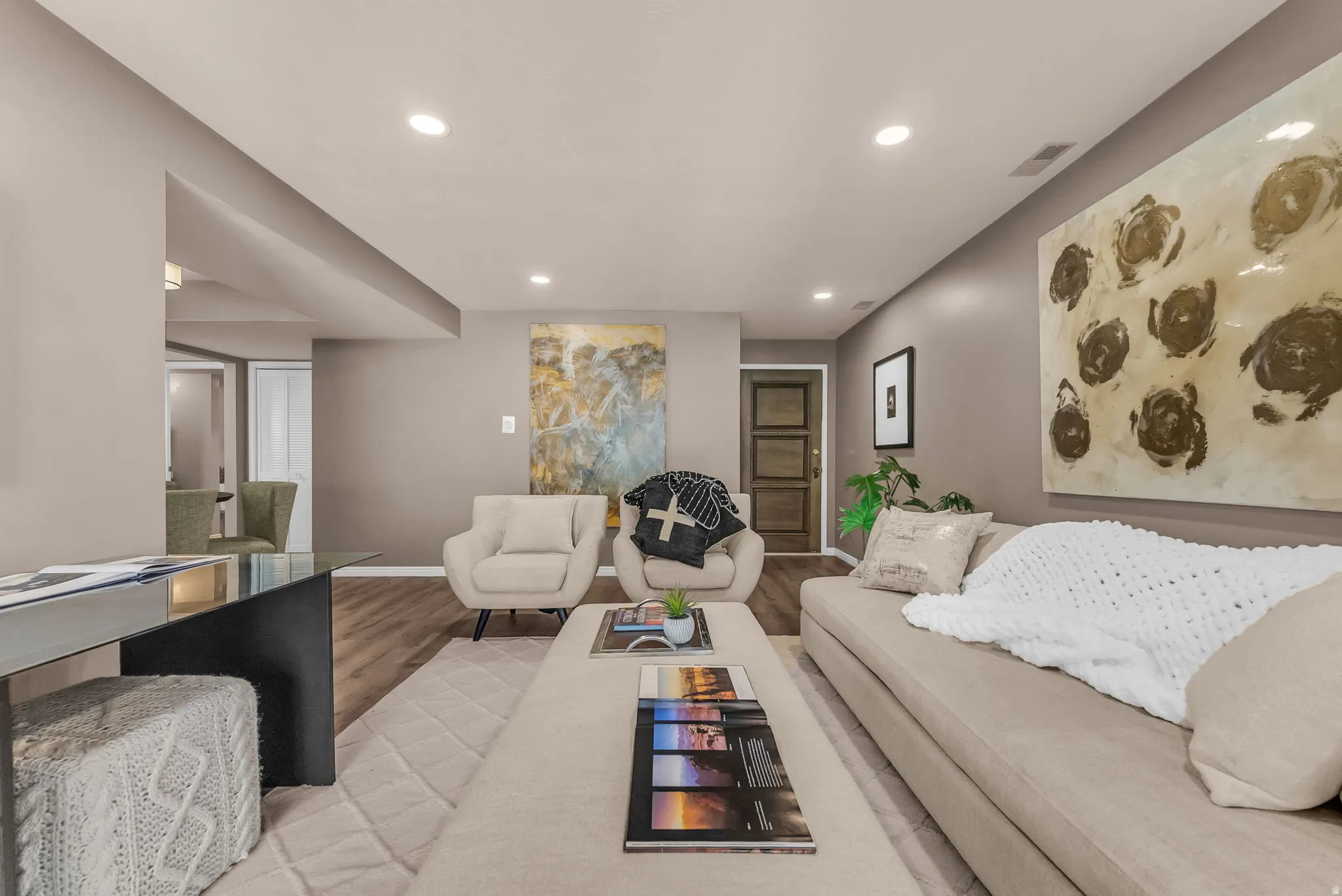 Recessed lighting illuminates the wood-finish flooring and light-toned walls
