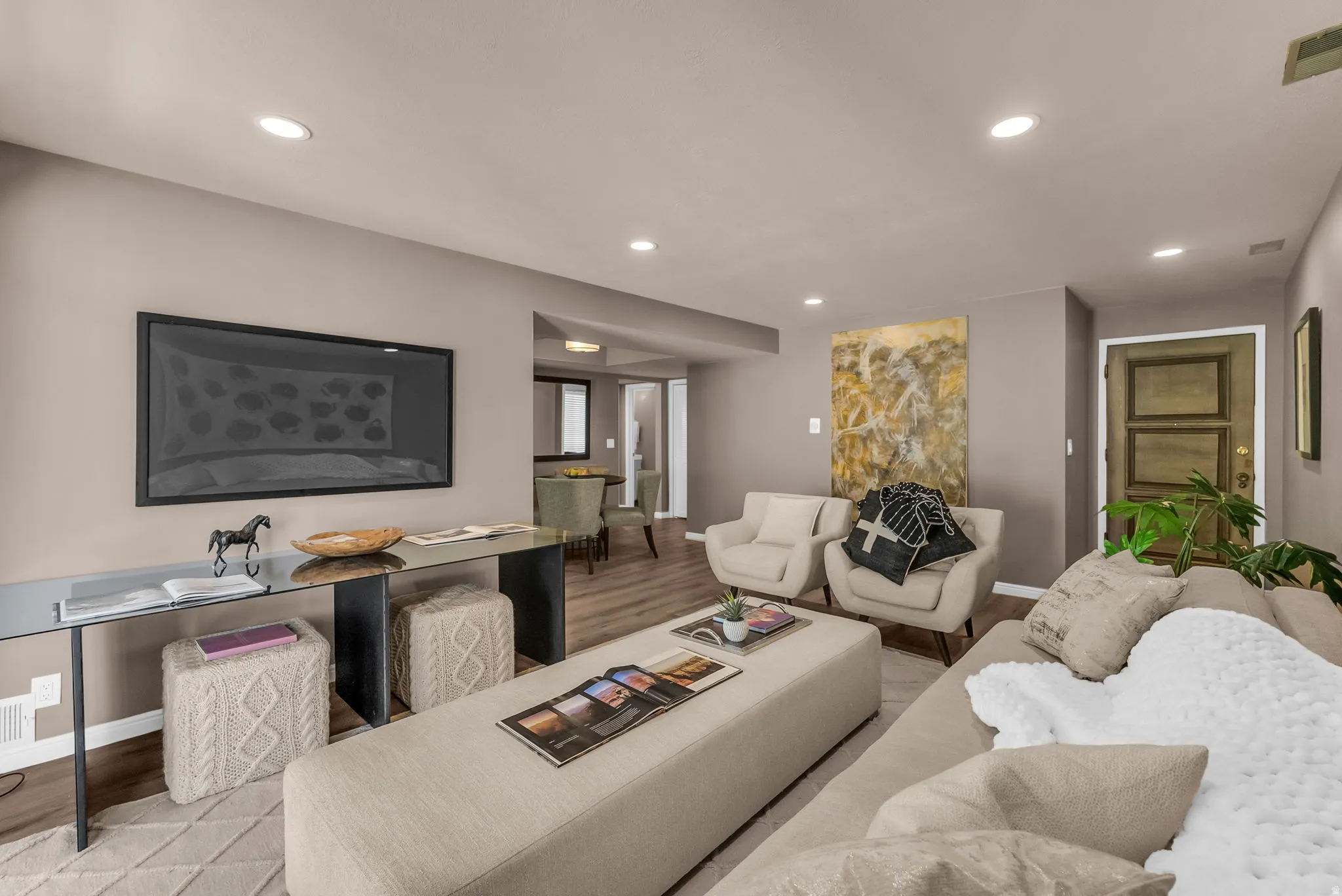 Open-concept living area featuring recessed lighting, wood-finish flooring, and a glass-top console table