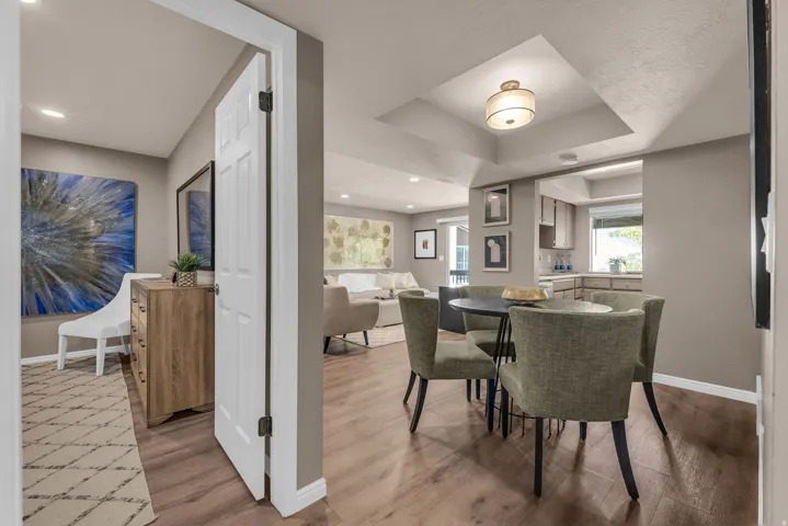 Recessed lighting, wood-finish flooring, tray ceiling with a semi-flush mount fixture, and a kitchen pass-through