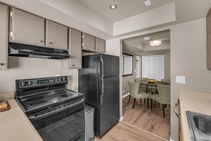 Kitchen featuring black appliances, light-toned cabinetry, and solid surface countertops