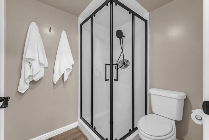 Corner shower with black framed enclosure and matte black fixtures