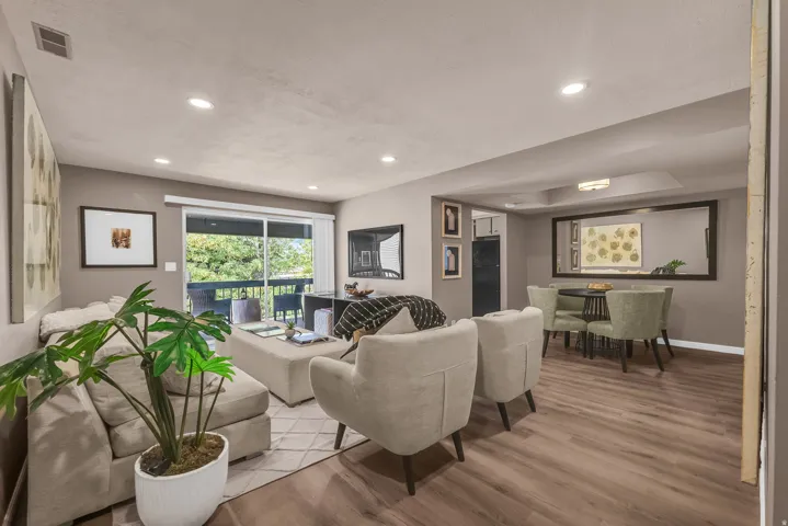 Open-concept living area featuring wood-finish flooring, recessed lighting, and a sliding glass door opening to a private balcony