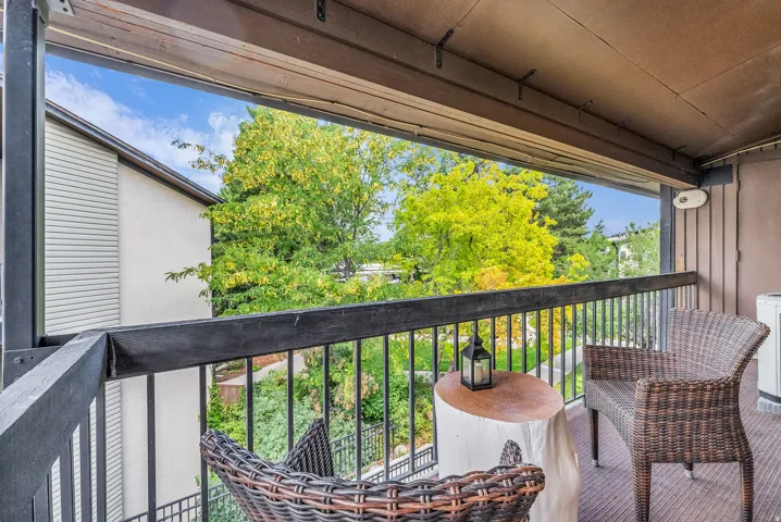 Covered balcony featuring a black metal railing and wood-finish flooring