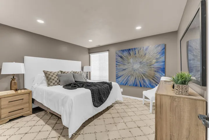 Recessed lighting, window with blinds, wood-finish dresser, and light-toned walls