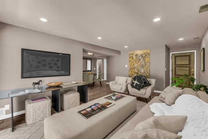 Open-concept living area featuring recessed lighting, wood-finish flooring, and a glass-top console table