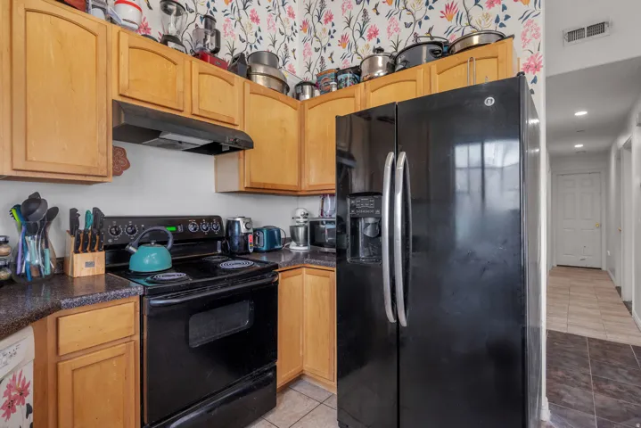 Kitchen featuring wood-finish cabinetry, black appliances, and durable countertop surfaces