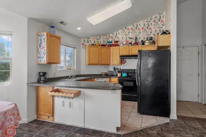 Kitchen featuring wood cabinetry, dark countertops, and tile flooring