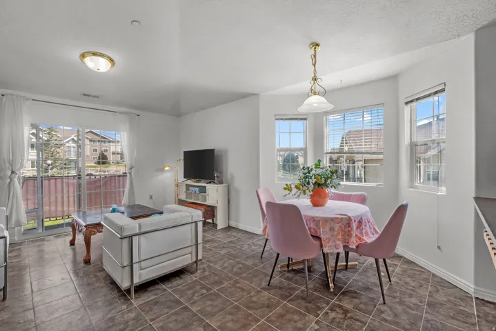 Tiled flooring extends throughout the space, complemented by a sliding glass door and multiple windows with blinds