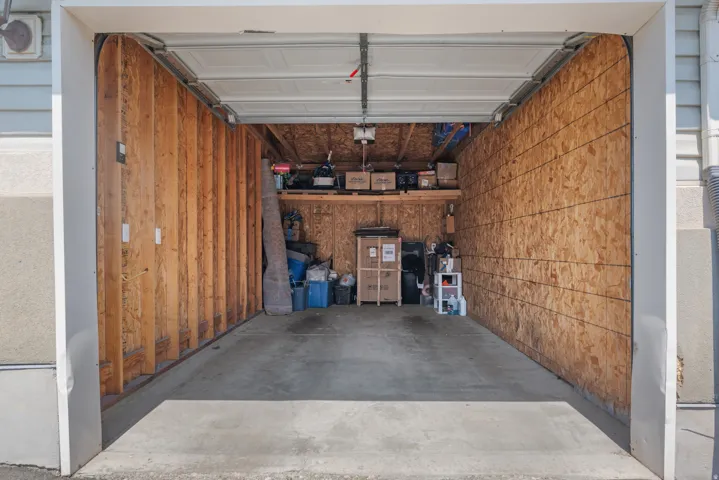 Attached garage featuring an overhead garage door, concrete flooring, and built-in shelving