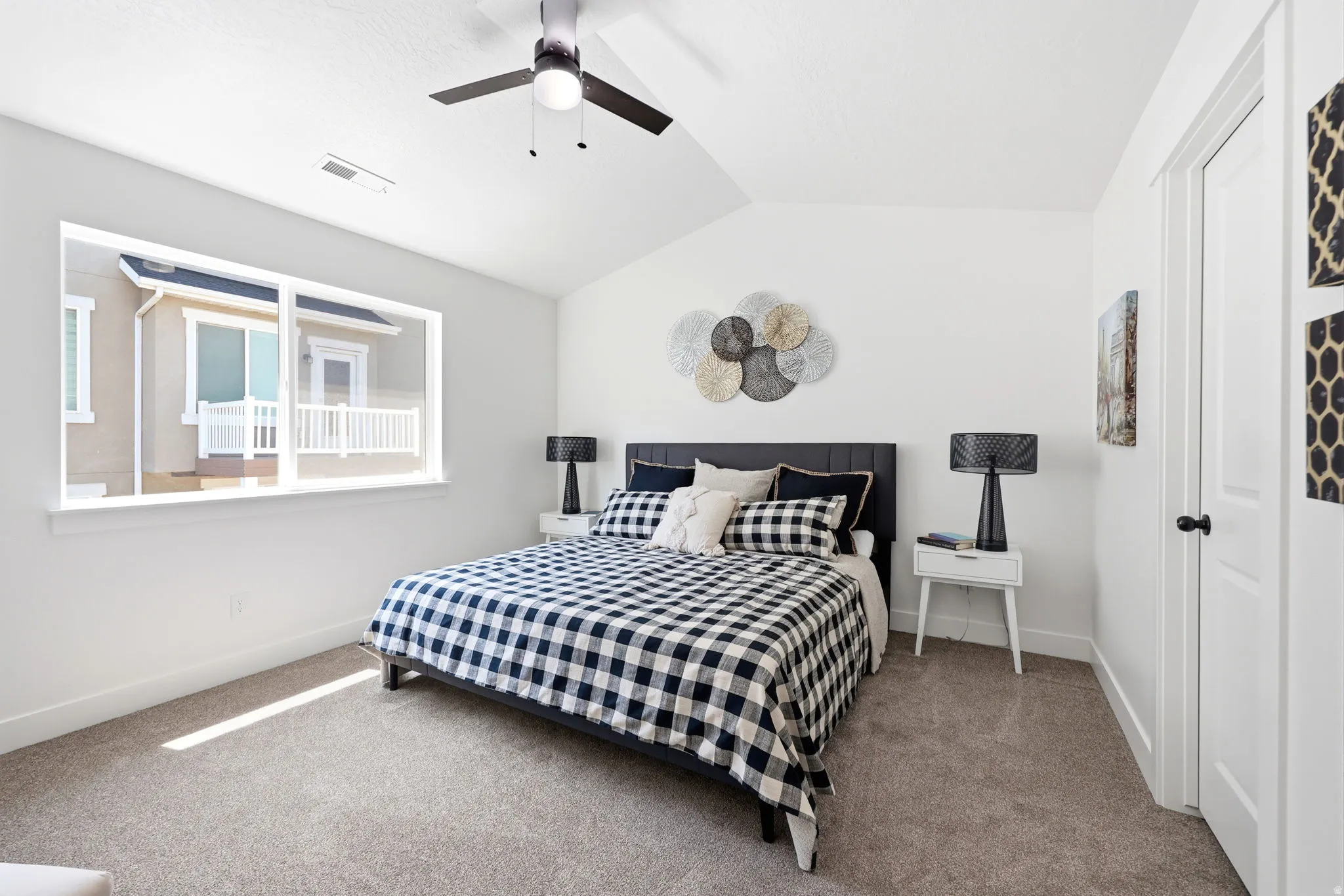 Carpeted bedroom featuring a vaulted ceiling and a ceiling fan with integrated lighting