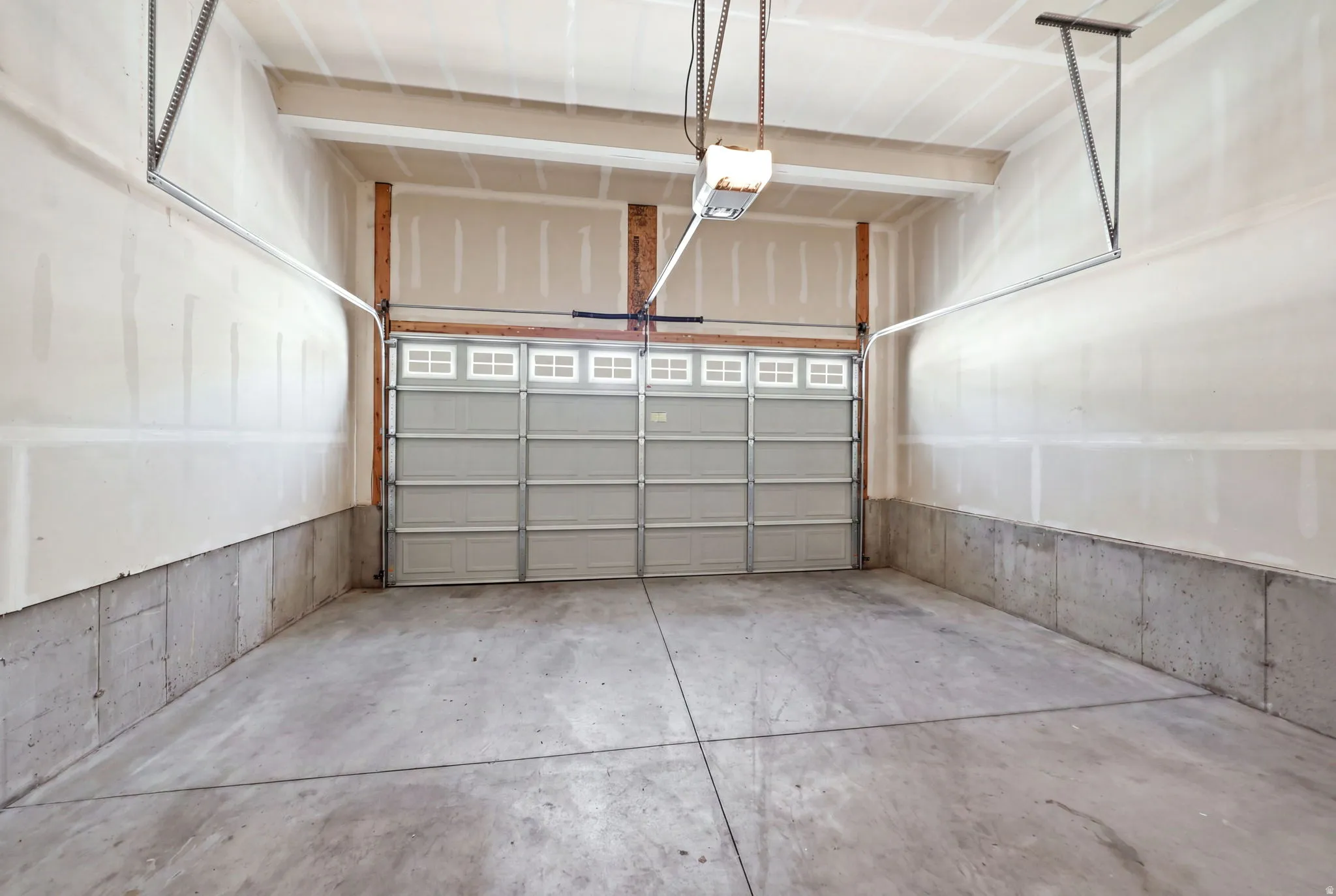 Spacious garage featuring a concrete floor, exposed wooden framing, and a large overhead door with window inserts