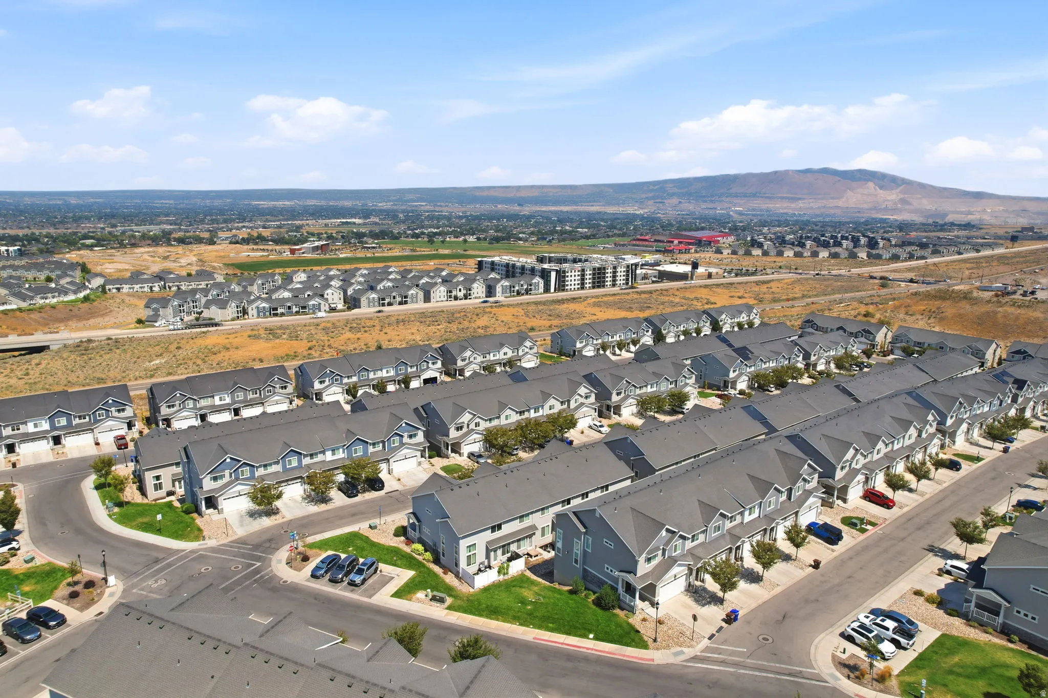 Community of modern townhomes featuring gray and blue exteriors, dark gray shingled roofs, private driveways, and integrated garages