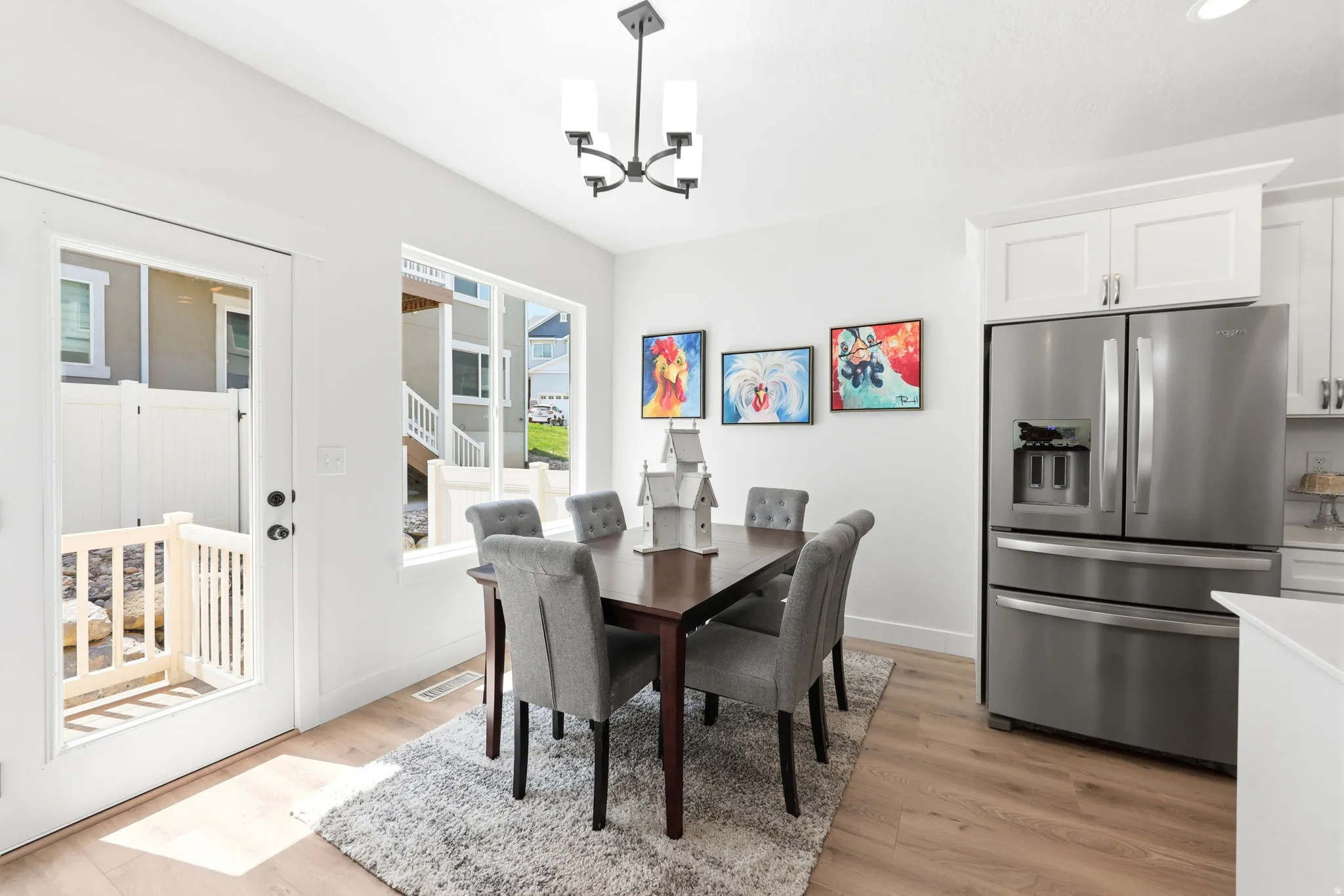 Dining area featuring light wood-finish flooring, white walls, and a contemporary chandelier