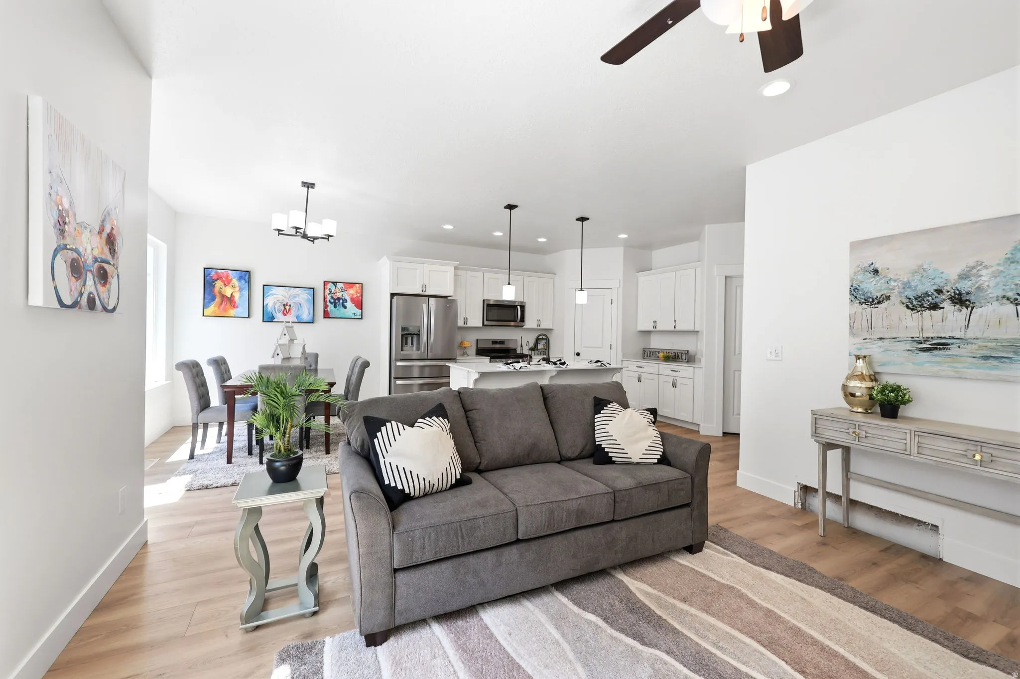Open-concept living area featuring light wood-finish flooring, recessed lighting, and a contemporary ceiling fan