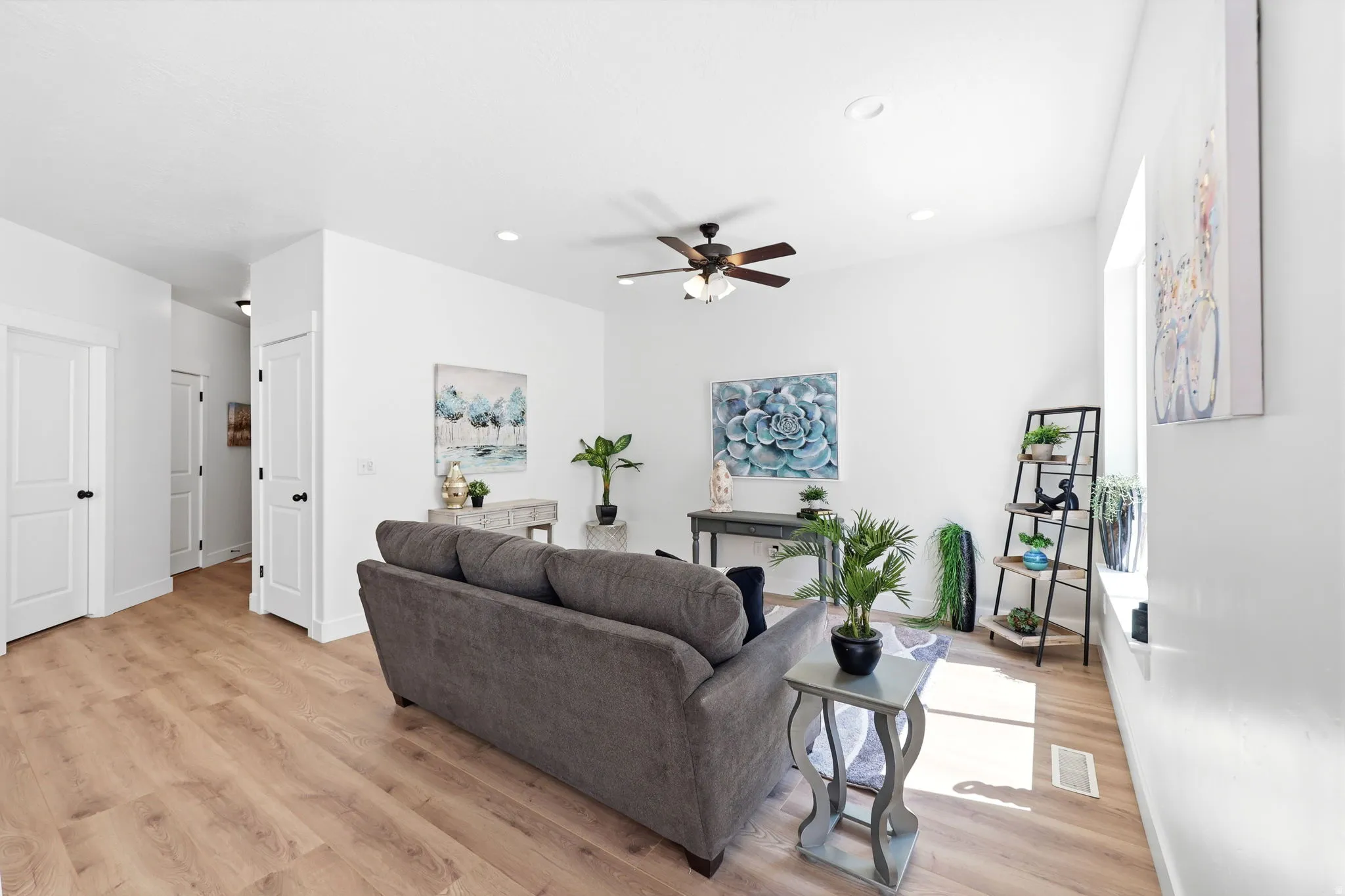 Bright living space featuring wood-finish flooring, recessed lighting, a ceiling fan, and white trim