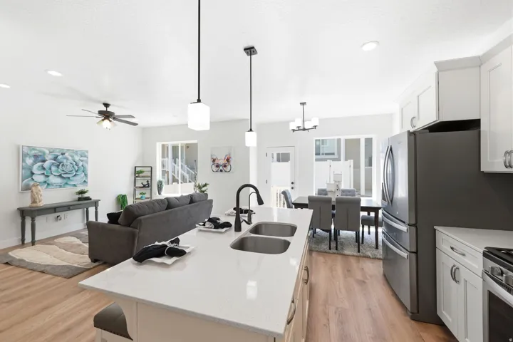 Open-concept living space with a kitchen island featuring a double sink, white cabinetry, and recessed lighting