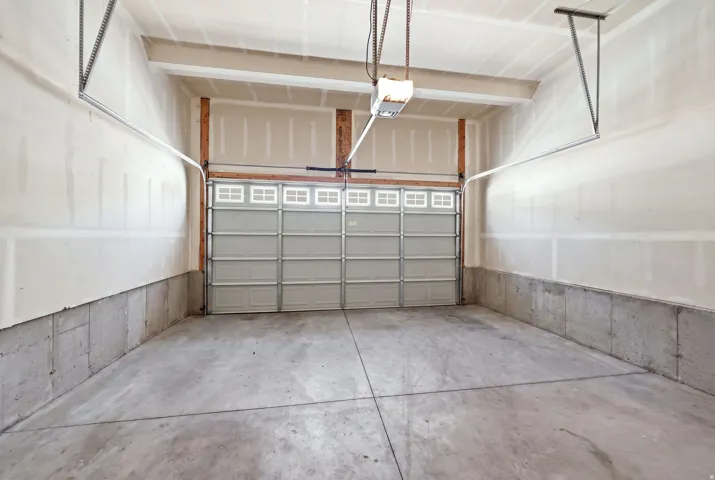 Spacious garage featuring a concrete floor, exposed wooden framing, and a large overhead door with window inserts