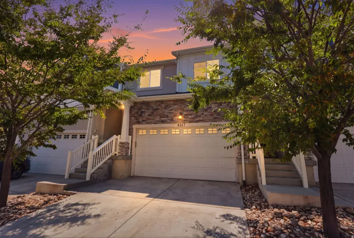 Stone facade detailing, two-story townhome featuring a private entrance, an attached two-car garage, and a concrete driveway