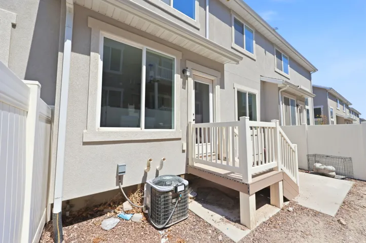 Rear exterior featuring a ground-level patio, an elevated composite deck with white railings, and a sliding glass door entry