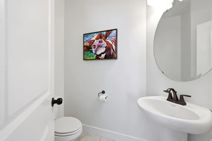 Pedestal sink with a bronze-finish faucet, accompanied by a round wall-mounted mirror