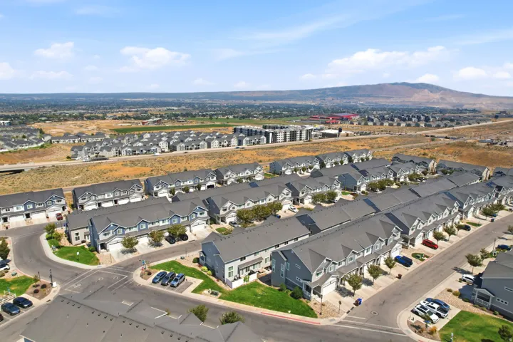 Community of modern townhomes featuring gray and blue exteriors, dark gray shingled roofs, private driveways, and integrated garages