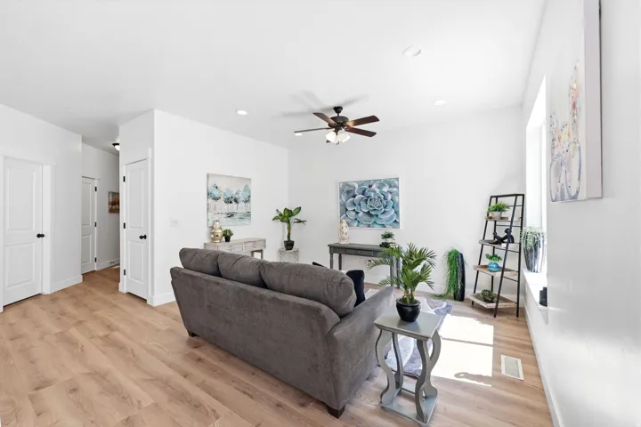 Bright living space featuring wood-finish flooring, recessed lighting, a ceiling fan, and white trim