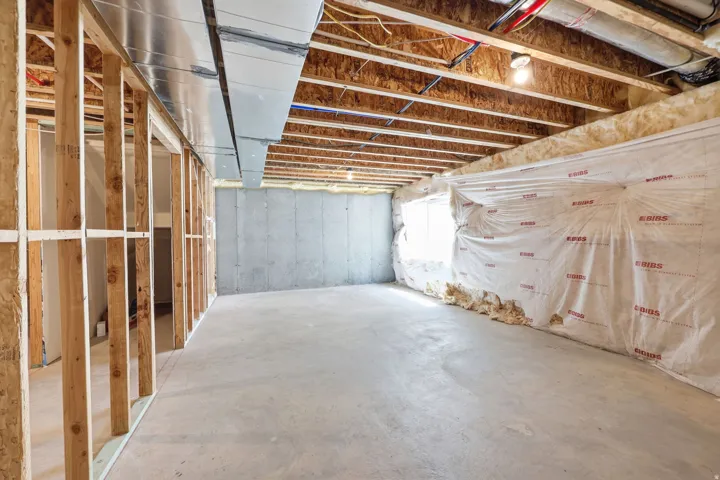 Unfinished basement space featuring exposed wood framing, concrete foundation walls, and a concrete floor